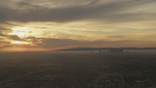 AF0001_000983 - 5K aerial stock footage of the setting sun behind clouds and the Downtown Los Angeles skyline, California