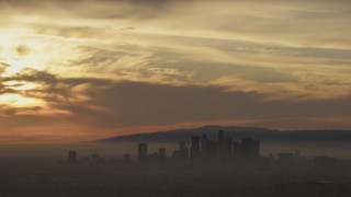 AF0001_000987 - 5K aerial stock footage of sunset-lit clouds above the Downtown Los Angeles skyline in haze, California