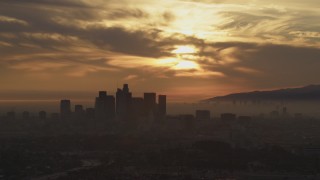 AF0001_000990 - 5K aerial stock footage of passing the hazy Downtown Los Angeles skyline at sunset, California