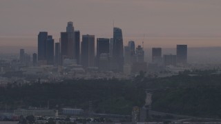 AF0001_000997 - 5K aerial stock footage of the Downtown Los Angeles skyline seen from behind Dodger Stadium at twilight, California