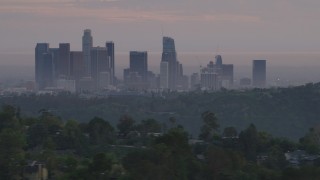 AF0001_000999 - 5K aerial stock footage of Downtown Los Angeles skyline seen while flying behind green hills and Dodger Stadium at twilight, California