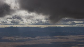 AF0001_001017 - 8K aerial stock footage of dark clouds over desert and mountain ridges in Southern California