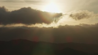 AF0001_001031 - 8K aerial stock footage of setting sun behind clouds and mountain ridges in Southern California