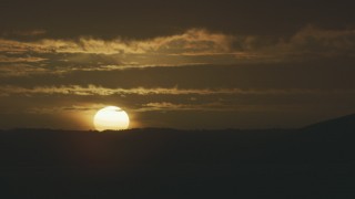 AF0001_001043 - 8K aerial stock footage of a view of the setting sun behind a mountain ridge, revealing an airport control tower, in Northern California