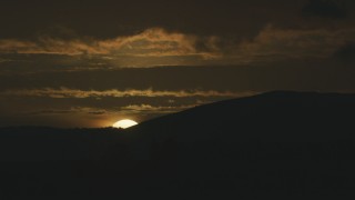 AF0001_001045 - 8K aerial stock footage of the setting sun disappearing behind a mountain ridge in Northern California