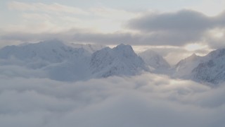 AK0001_0010 - 4K aerial stock footage pan by snow covered peaks above low clouds, Chugach National Forest, Alaska