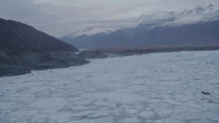 AK0001_0055 - 4K aerial stock footage flying over an ice covered lake, tilt up to reveal Chugach Mountains, Knik, Alaska