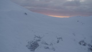 AK0001_0090 - 4K aerial stock footage approach snow covered summit, reveal sunset, Chugach Mountains, Alaska, sunset