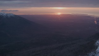 AK0001_0094 - 4K aerial stock footage snow covered slope, revealing Anchorage, Chugach Mountains, Alaska, sunset