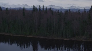 AK0001_0173 - 4K aerial stock footage over wooded shoreline, reveal Downtown Anchorage, Point MacKenzie, Alaska