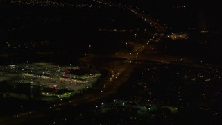 AK0001_0199 - 4K aerial stock footage flying by shopping center, tilt up following Glenn Highway, Anchorage, Alaska, night