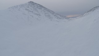 AK0001_0231 - 4K aerial stock footage ascend snowy peak, reveal snow capped mountains, Chugach Mountains, Alaska