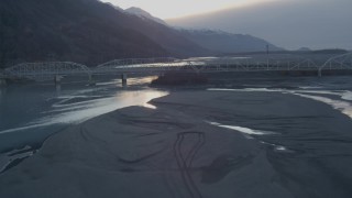 AK0001_0303 - 4K aerial stock footage lift off shore, follow Knik River, Old Glenn Highway bridge, Knik River, Alaska, sunset