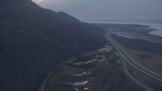 AK0001_0314 - 4K aerial stock footage flying over Glenn Highway, pan right to reveal highway, Knik River, Alaska, twilight