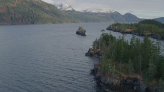AK0001_0402 - 4K aerial stock footage flying by forested shoreline, small island, open waters, Passage Canal, Alaska