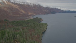 AK0001_0482 - 4K aerial stock footage fly over forested shoreline, approach snow capped peaks, Blackstone Bay, Alaska