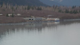 AK0001_0507 - 4K aerial stock footage flying low over water, by a docked boat, Portage Lake, Alaska