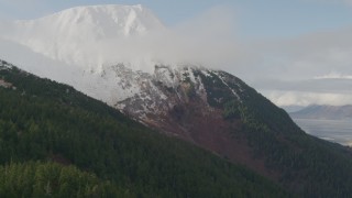AK0001_0525 - 4K aerial stock footage flying up wooded slope toward snow capped peak, Kenai Mountains, Alaska