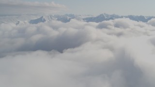 AK0001_0536 - 4K aerial stock footage flying over low clouds, by snow capped peaks, Kenai Mountains, Alaska