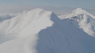 AK0001_0539 - 4K aerial stock footage approaching snowy mountains, flying up a snowy slope, Kenai Mountains, Alaska