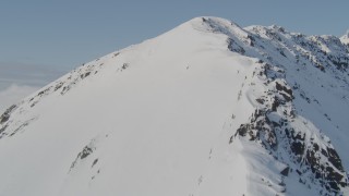 AK0001_0542 - 4K aerial stock footage ascending a snowy ridge, flying along the slopes, Kenai Mountains, Alaska
