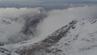 AK0001_0570 - 4K aerial stock footage flying by snow capped mountains, with low clouds, Chugach Mountains, Alaska
