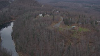 AK0001_0650 - 4K aerial stock footage approaching homes atop wooded hills, near river, distant valley, Birchwood, Alaska