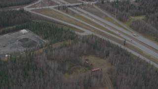 AK0001_0665 - 4K aerial stock footage following Glenn Highway, wooded area, by an overpass, Eagle River, Alaska