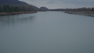 AK0001_0701 - 4K aerial stock footage flying low over riverbank, river lined with trees, during winter, Knik River, Alaska