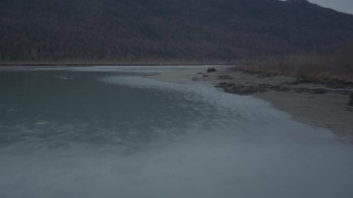 AK0001_0704 - 4K aerial stock footage flying low over river, approaching tree-lined shore, winter, Knik River, Alaska