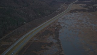 AK0001_0707 - 4K aerial stock footage following highway by marshlands, forest, during winter, Glenn Highway, Alaska