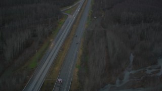 AK0001_0708 - 4K aerial stock footage following highway through forest during winter, Glenn Highway, Alaska