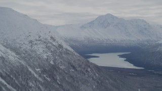AK0001_0776 - 4K aerial stock footage flying by snow-covered Chugach Mountains bordering Eklutna Lake, Alaska