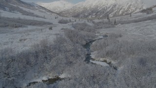 AK0001_0802 - 4K aerial stock footage flying low over river, frosty valley, snow-covered Chugach Mountains, Alaska