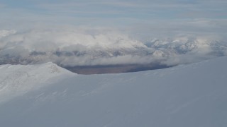 AK0001_0816 - 4K stock footage aerial video over snowy ridge, reveal Matanuska River Valley, Chugach Mountains, Alaska