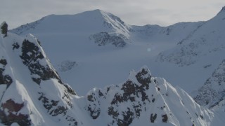 AK0001_0827 - 4K aerial stock footage flying over snow-covered rocky ridge, pan across Chugach Mountains, Alaska