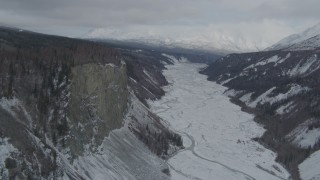AK0001_0880 - 4K aerial stock footage approaching tree lined cliff over snowy Matanuska River Valley, Alaska