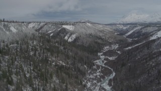 AK0001_0883 - 4K aerial stock footage flying over snowy gorge and icy river during winter, near Sheep Mountain, Alaska