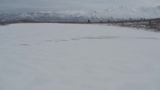 AK0001_0890 - 4K aerial stock footage flying low over snow-covered frozen Goober Lake, Alaska