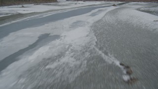 AK0001_0900 - 4K aerial stock footage flying low over the icy, snow covered river during winter, Tazlina River Valley, Alaska