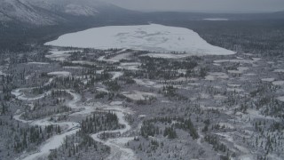 AK0001_0955 - 4K aerial stock footage flying by icy rivers and snow covered ground, during winter, revealing Kaina Lake, Alaska