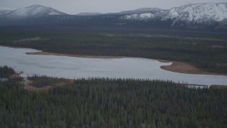 AK0001_0965 - 4K aerial stock footage flying over lake surrounded by forest during winter, Saint Anne Lake, Alaska
