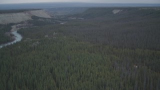 AK0001_0971 - 4K aerial stock footage fly over edge of cliff, during winter, revealing forest, and the Klutina River, Alaska