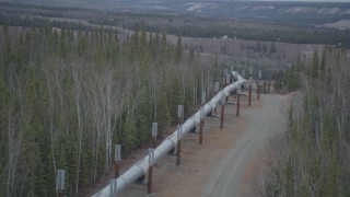 AK0001_0988 - 4K aerial stock footage follow pipeline down hill through forest, during winter, Trans-Alaska Pipeline, Alaska
