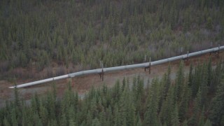 AK0001_0991 - 4K aerial stock footage approach and orbit pipeline emerging from ground, winter, Trans-Alaska Pipeline, Alaska