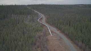 AK0001_0992 - 4K aerial stock footage orbiting pipeline emerging from ground, winter, Trans-Alaska Pipeline, Alaska