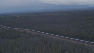 AK0001_1013 - 4K aerial stock footage flying over a snow covered lake and forest revealing Trans-Alaska Pipeline, Alaska