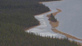 AK0001_1033 - 4K aerial stock footage forest and an island on snow covered shore of Sucker Lake, Alaska