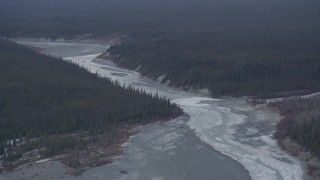 AK0001_1044 - 4K aerial stock footage the icy Tazlina River surrounded by evergreen forest, Alaska