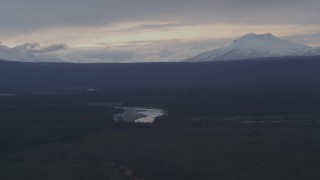 AK0001_1045 - 4K aerial stock footage flying over forest toward the Tazlina River and snow capped mountains, Alaska